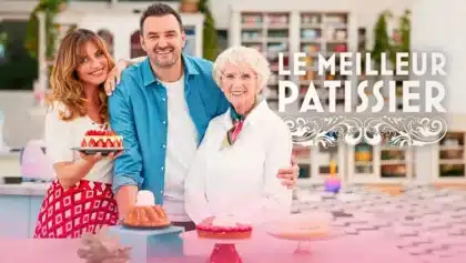 Les animateurs de l’émission Le Meilleur Pâtissier posent souriants avec des gâteaux sur le plateau du concours culinaire.