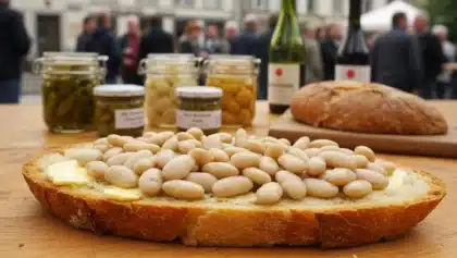 Tartine vendéenne garnie de mogettes au beurre, posée sur une table en bois avec bocaux et vin du terroir à l’arrière-plan.