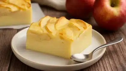 Part de flan aux pommes maison, doré au four et servi dans une assiette avec une cuillère.