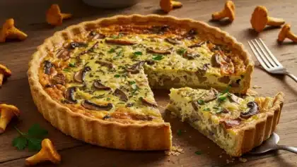 Quiche forestière dorée garnie de champignons, d’œufs et de crème, servie sur une table en bois avec quelques girolles fraîches autour.