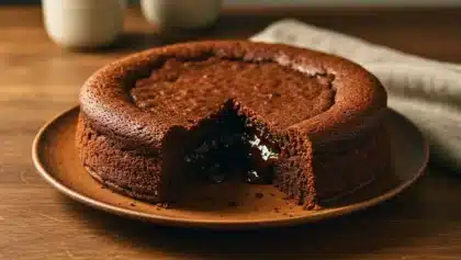 Fondant au chocolat entier avec une part retirée laissant apparaître un cœur coulant brillant.