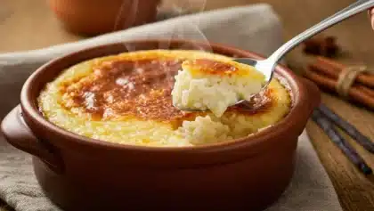 Ramequin de riz au lait crémeux cuit au four, avec une cuillère montrant la texture fondante et la surface dorée.