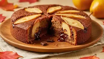 Gâteau moelleux au chocolat décoré de tranches de poire et garni d’un cœur fondant au chocolat, présenté sur une assiette en bois.