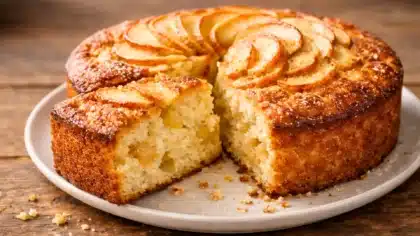 Gâteau aux pommes et mascarpone moelleux, doré au four, avec une part découpée montrant une texture fondante