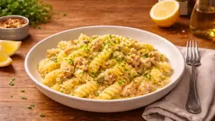 Assiette de pâtes au thon citronnées, sauce onctueuse sans crème, servies dans une assiette creuse sur table en bois.