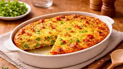 Quiche sans pâte aux lardons et petits pois, dorée et moelleuse, avec une part découpée révélant un cœur crémeux.
