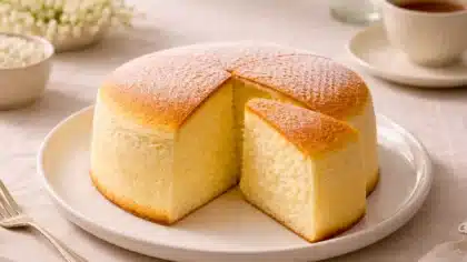 Un cheesecake japonais soufflé, léger et moelleux, présenté sur une assiette blanche avec une part découpée, dans une ambiance douce de goûter.