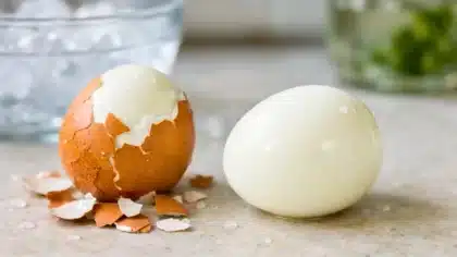 Deux œufs durs sur un plan de cuisine, dont un parfaitement écalé et lisse, à côté d’un autre encore partiellement dans sa coquille.